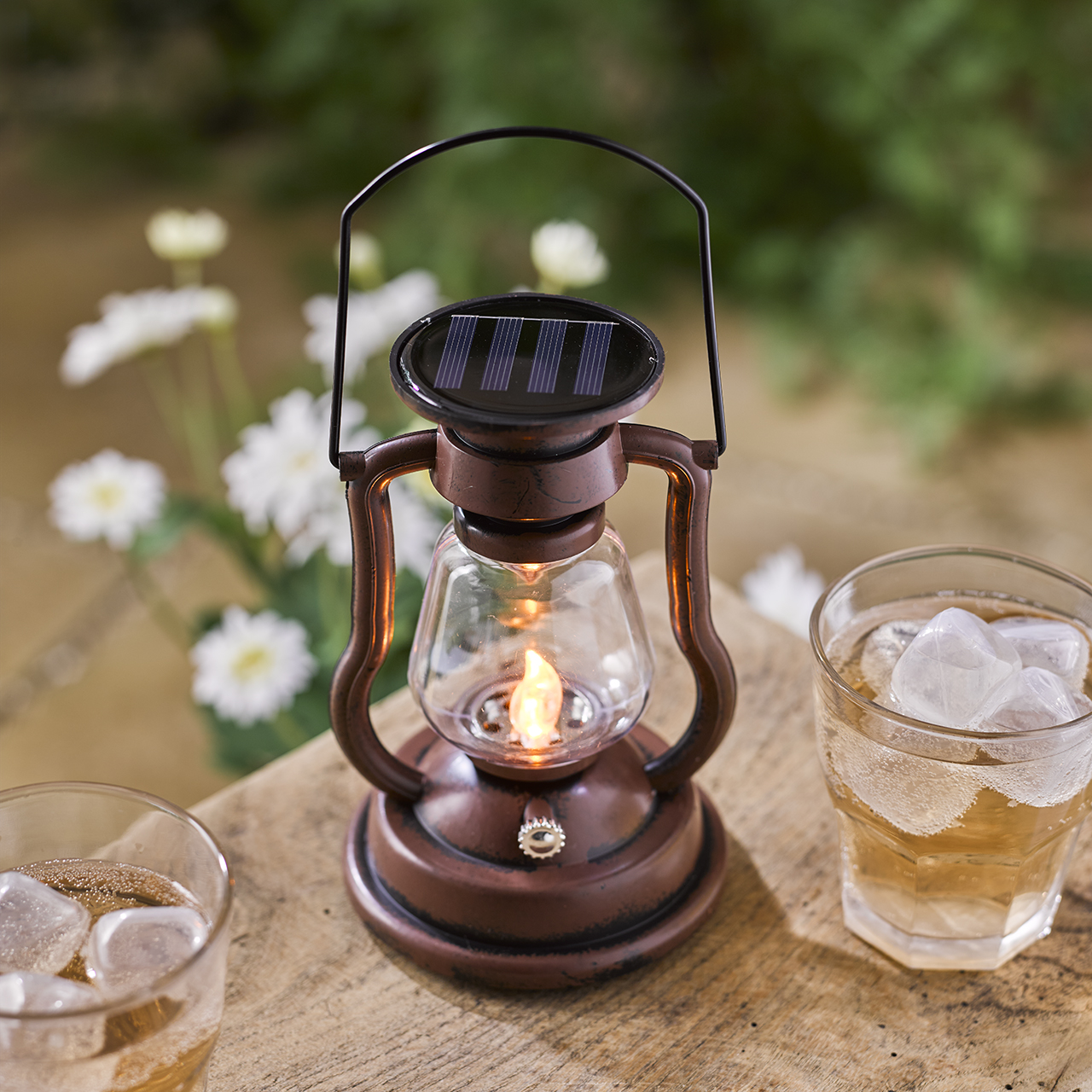 Bronze-coloured solar lantern glowing on an outdoor table