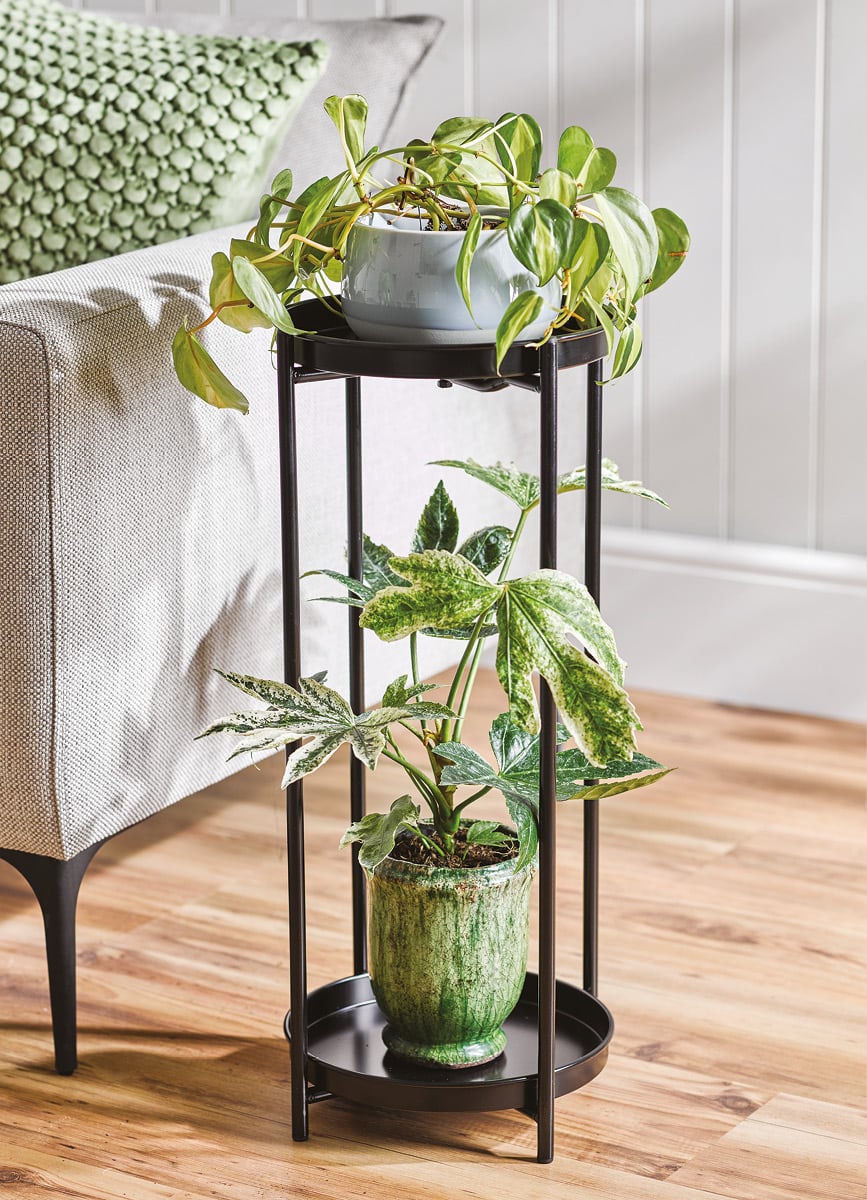 Black two tier plant stand with faux plants on