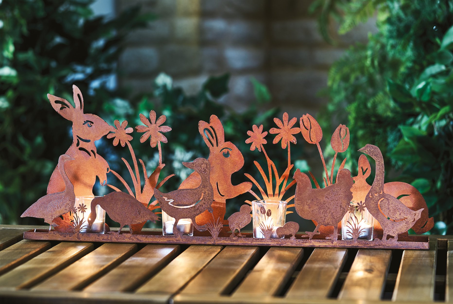 Rust silhouettes of rabbits, chickens and flowers surrounding four glass tea light holders
