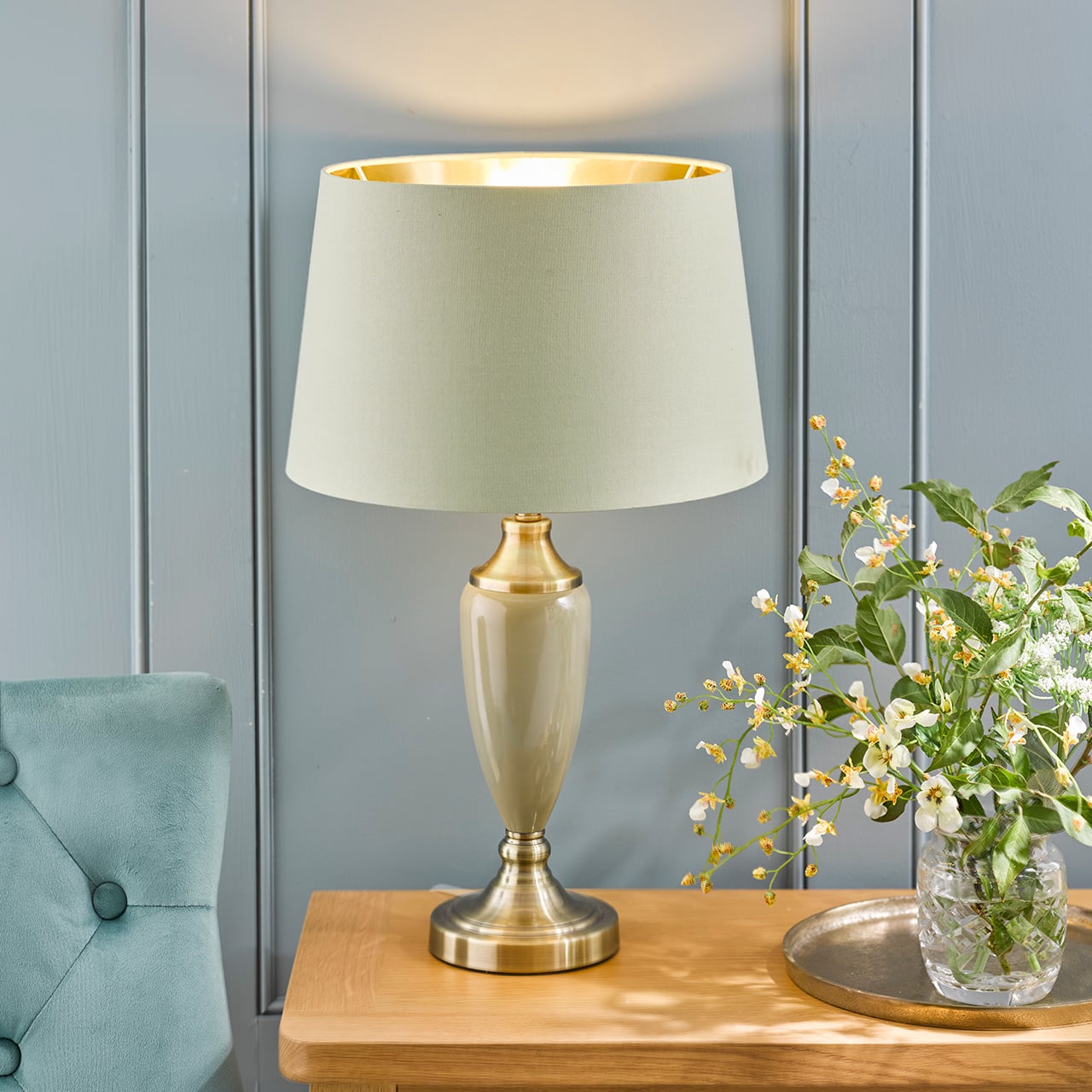Green table lamp with a white shade on a bedside table
