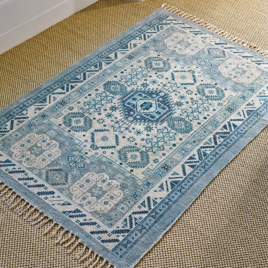 A blue patterned rug with tassels